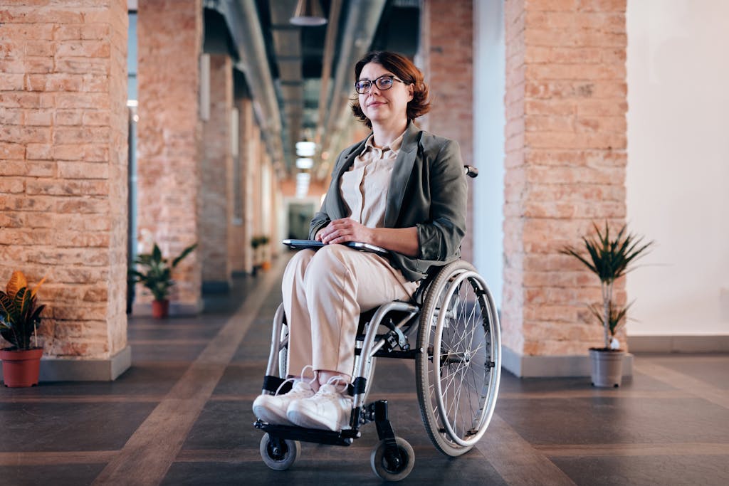 Confident businesswoman in wheelchair smiling indoors in a modern office.